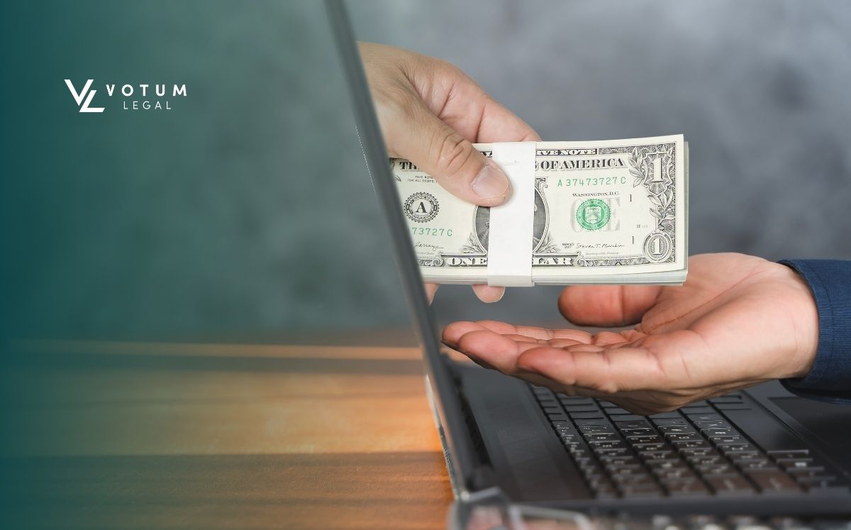 kredyt-w-dolarach (1) Otwarty laptopa a z niego wyłania się dłoń z gotówką